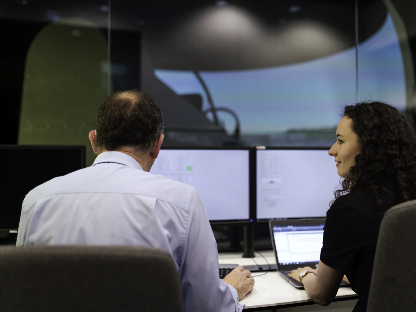 Two colleagues reviewing work together at an operations desk.